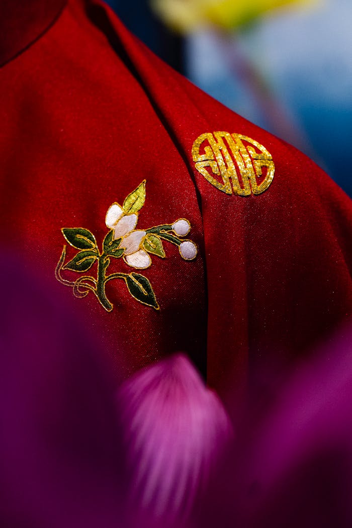 Close-up of red fabric with intricate floral embroidery and gold Chinese symbols.